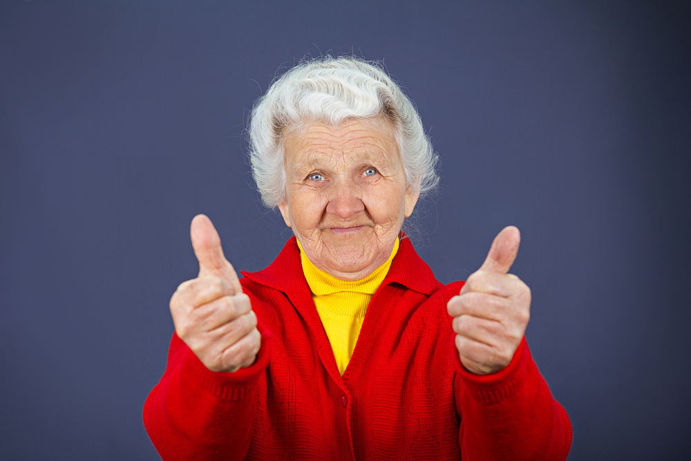 Closeup portrait senior, mature, happy, smiling excited natural woman giving thumbs up sign with fingers, isolated blue background. Positive emotions, facial expressions, symbols, feelings, attitude Closeup portrait senior, mature, happy, smiling excited natural woman giving thumbs up sign with fingers, isolated blue background. Positive emotions, facial expressions, symbols, feelings, attitude