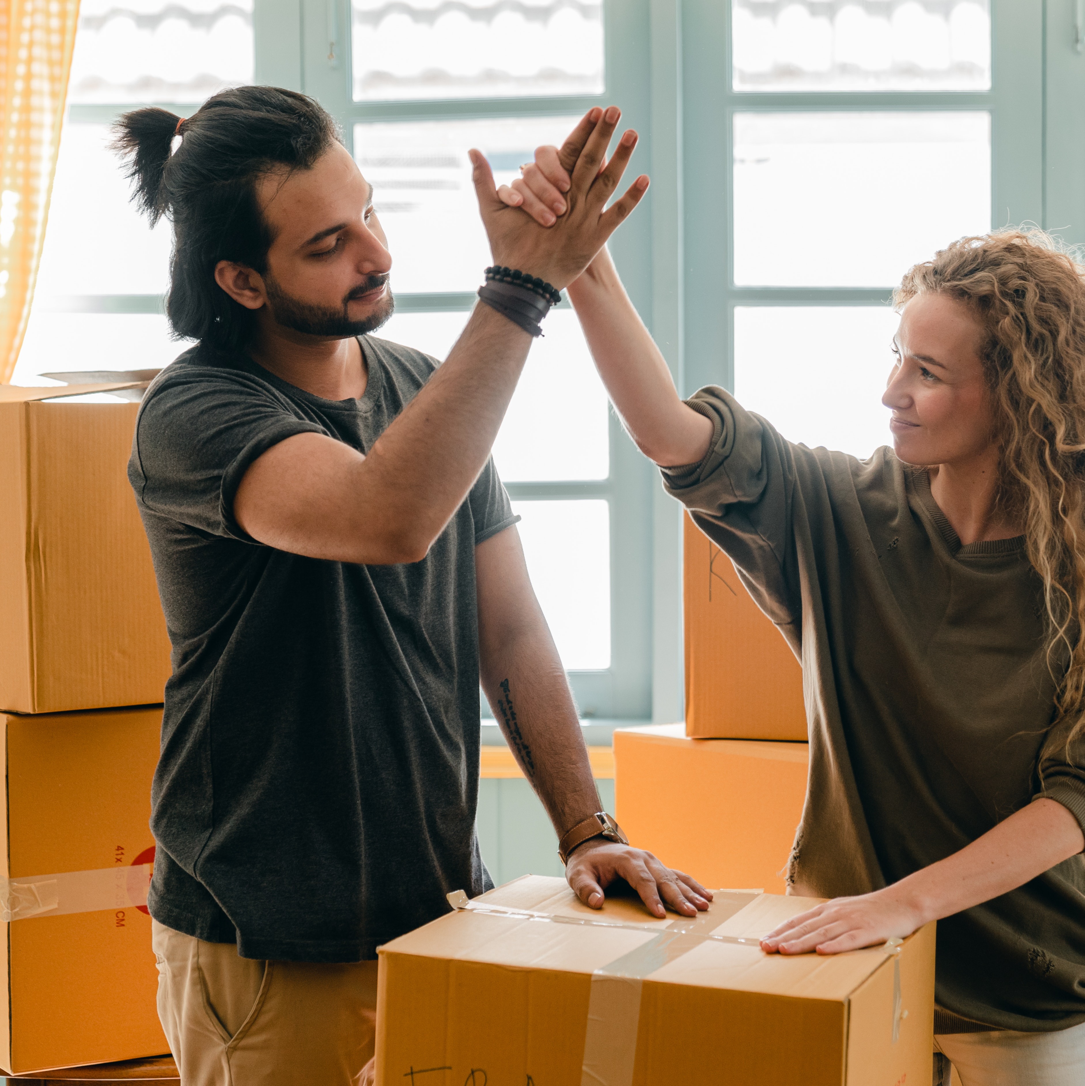 Couple giving each other a high five surrounded by moving boxes